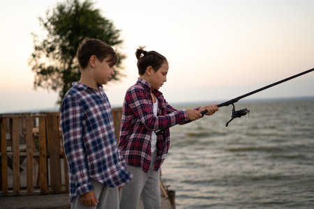 boys is fishing at sunset on the lakeの写真素材