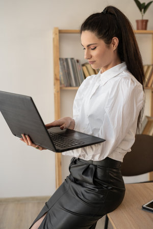 Portrait of a young business woman working with a laptop in office, successful middle-aged businesswomanの写真素材
