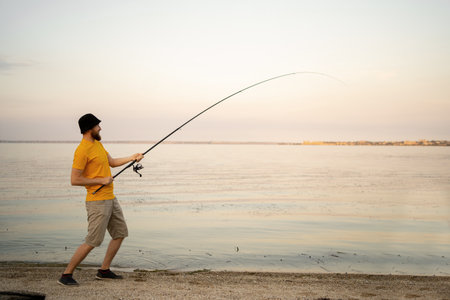 Young man fishing in a pond in a sunny day. fisherman outdoor leisure lifestyle.の写真素材