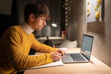 College student studying at night in dormitory using laptop computer. copy spaceの写真素材
