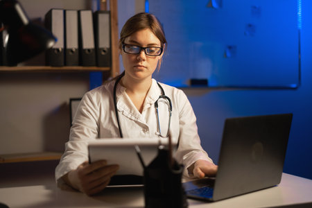 Female doctor writing on clipboard while sitting in front of laptop at doctors office. copy spaceの写真素材