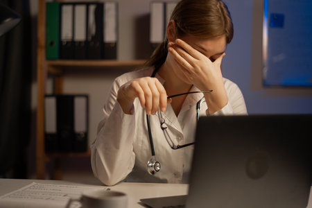Tired doctor or nurse sitting at table during night shift. copy spaceの写真素材