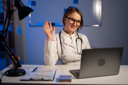 Online video chat by doctor. Female doctor working at hospital office during night shift using laptop computer for video call. copy spaceの写真素材