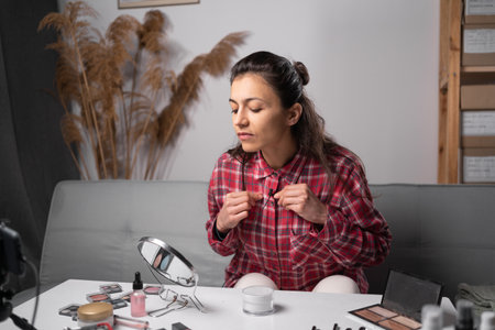 Young beautiful woman professional beauty vlogger preparing to do recording a make up tutorial. Girl recording her video blog episode about new cosmetic products at her living room. copy spaceの写真素材
