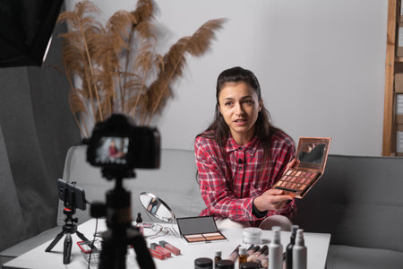 Beautiful hispanic woman reviewing beauty products on a video blog at home. Vlogger selfie shoot enjoy work teach how making make up. copy spaceの写真素材
