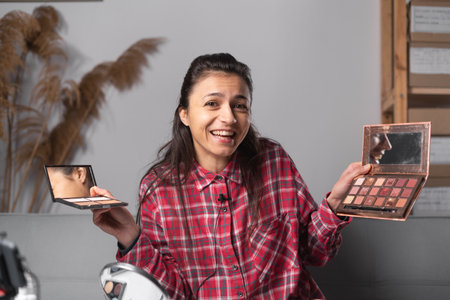 Vlogger female showing eye shadow palette. Influencer girl live streaming cosmetics product review in home studio. Business online influencer on social media concept. copy spaceの写真素材
