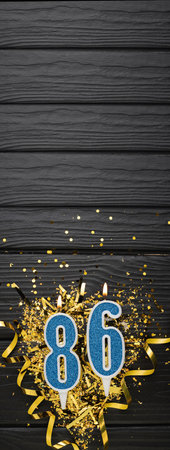 Number 86 blue celebration candle and gold confetti on dark wooden background. 86th birthday card. Anniversary and birthday concept. vertical banner. copy spaceの写真素材