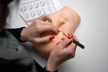 Person with a mannequin training head practicing lash extension techniques. Training eyelash extensions concept. copy spaceの写真素材
