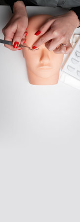 Training eyelash extensions concept. Work on extensions of eyelashes on a mannequin. vertical banner. copy spaceの写真素材