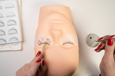 Basic training to build eyelashes on a silicone mannequin. Eyelashes close-up. Work with tweeter. Eyelash extension procedure. copy spaceの写真素材