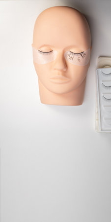 Beauty background with eyelash extension theme. A mannequin training head with strip lashes is set out. Training eyelash extensions.の写真素材