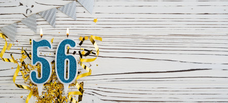 Number 56 blue celebration candle on white wooden background. Happy birthday for fifty-six years old. Copy space.の写真素材