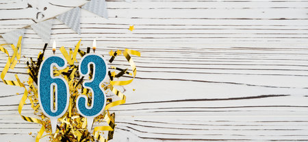 Number 63 blue celebration candle on white wooden background. Happy birthday candles. Concept of celebrating birthday, anniversary, important date, holiday. Copy space.の写真素材