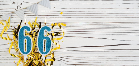 Number 66 blue celebration candle on white wooden background. Happy birthday candles. Concept of celebrating birthday, anniversary, important date, holiday. Copy space.の写真素材