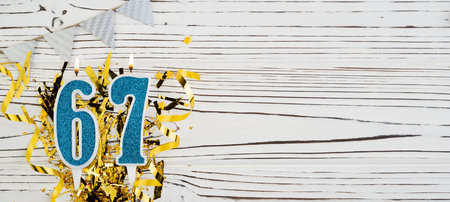 Number 67 blue celebration candle on white wooden background. Happy birthday candles. Concept of celebrating birthday, anniversary, important date, holiday. Copy space.の写真素材