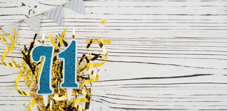 Number 71 blue celebration candle on white wooden background with golden foil. Copy space.の写真素材