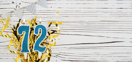 Number 72 blue celebration candle on white wooden background with golden foil. Copy space.の写真素材