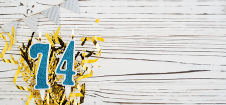 Number 74 blue celebration candle on white wooden background with golden foil. Copy space.の写真素材