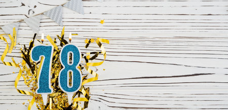 Number 78 blue celebration candle on white wooden background with golden foil. Copy space.の写真素材