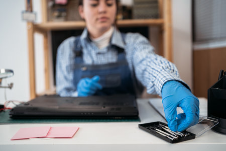Technician repairing broken laptop notebook computer with a screwdriver. Unscrewing the screws from the laptop case with a screwdriver for its repair and maintenance.の写真素材