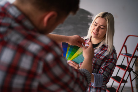 Young couple with palette selecting color of wall during repair at home, close-up. Home, moving, decoration, renovation, and wall paintingの写真素材