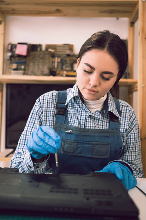 Computer repair shop. Engineer performing laptop maintenance unscrew the laptop case using a screwdriver.の写真素材