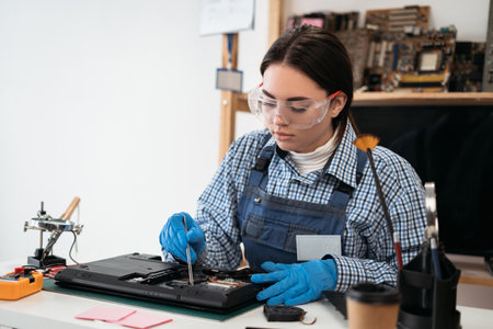 Woman repairing the broken laptop computer in service office. Computer service and repair concept.の写真素材