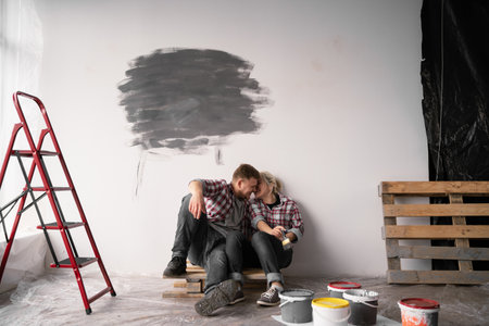 Happy young couple smiling each other while having break during repairment. Repair, building and home conceptの写真素材