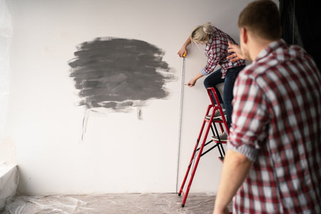 Repair home concept. Young woman measuring a wall with measuring tape, man help her.の写真素材