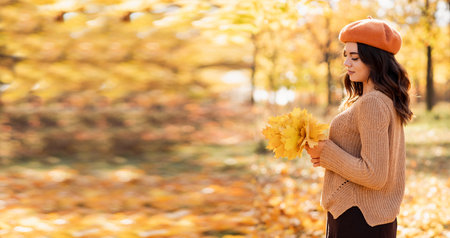 Autumn walk. Woman portrait. Dreaming girl holding maple leaves bouquet. Women enjoying fall nature. Banner.の写真素材