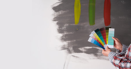 House painter woman decorator choose the color using the sample swatch, close up. Work the white wall of the house to renovate. Banner.の写真素材