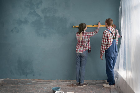 Repair home concept. A young couple are measuring a wall with spirit level.の写真素材