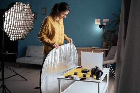 Professional photographer taking picture of beauty products in home studio, using reflector and diffuser. Taking pictures of cosmetics in small photo studio. copy spaceの写真素材