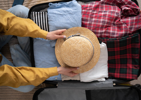 Woman packing suitcase at home, top view. Packed suitcase with accessories. travel conceptの写真素材