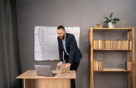 remote education concept. Happy male teacher giving online English lesson using laptop and...