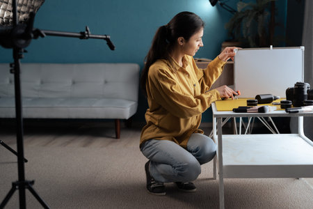 Female photographer preparing for the shooting laying out props on the table. Home studio with...