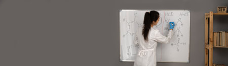Rear view of chemistry teacher who draws on the blackboard formulas and elements, signs and symbols of chemistry, the concept of the study of substances, organic chemistryの写真素材