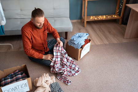Man packing his old uses clothes into donation box in living room, top view. Donation concept.の写真素材