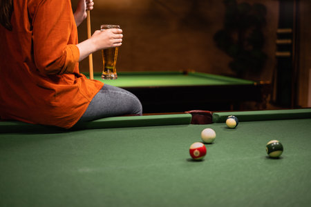 Woman drinking beer on pool table while playing snooker gameの写真素材