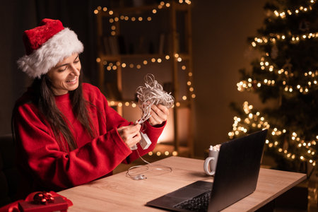 Young woman christmas shopping online unwinds garland for home or small office decorationの写真素材