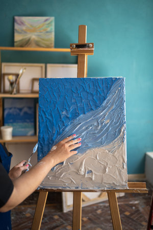 Hand drawn oil painting. Female painter near abstract art in her studio. Oil painting on canvas. Color texture. Modern art. Colorful canvas. Hobby, work, art and life conceptの写真素材