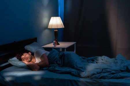 Young arabic man sleeping in bed at home at night. People, bedtime and rest conceptの写真素材