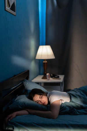 Woman suffering from insomnia lying in bed with open eyes. Girl in bed sleep disorder thinking about problems at nightの写真素材