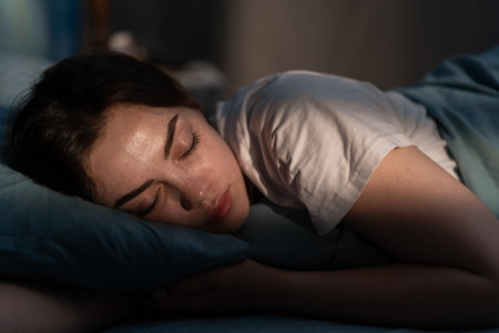 Portrait of beautiful young woman sleeping cozily on a bed in her bedroom at night.の写真素材