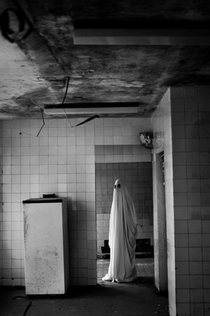 White ghostly figure in abandoned room, haunted house interior, atmosphere with old things. Halloween concept. Copy spaceの写真素材