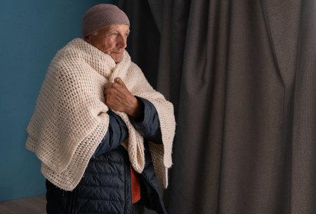 Elderly man suffers in a cold house, heating is cut off for non-payment, the poor old man is unable to pay for heatの写真素材
