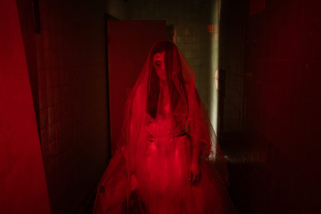 Bride of the dead, ghost woman in a white dress walking through an old building or haunted house,...
