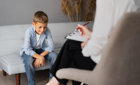Professional child psychologist working with a schoolboy in a bright office. Childrens mental therapyの写真素材