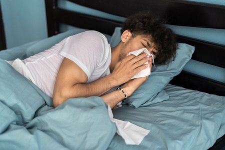 Cold and flu concept. Sick man suffering from running stuffy nose. Upset ill guy blowing her nose using paper napkin tissue.の写真素材