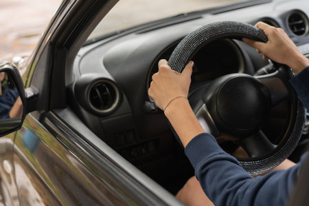 Close-up of a womans hands, holding the steering wheel, while driving with a sunset background.の写真素材